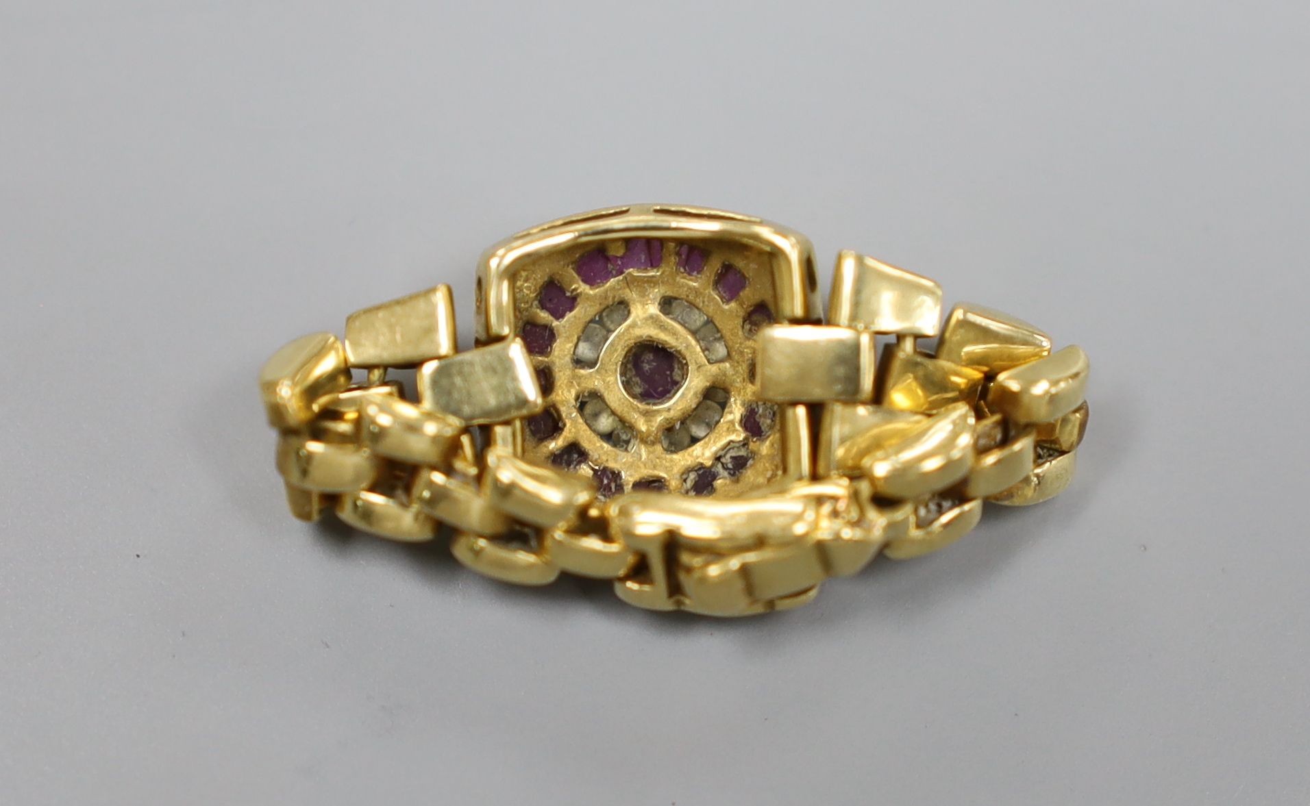 A modern 750, ruby and diamond circular cluster set ring, with articulated shank and clasp, size S. gross weight 8.4 grams.